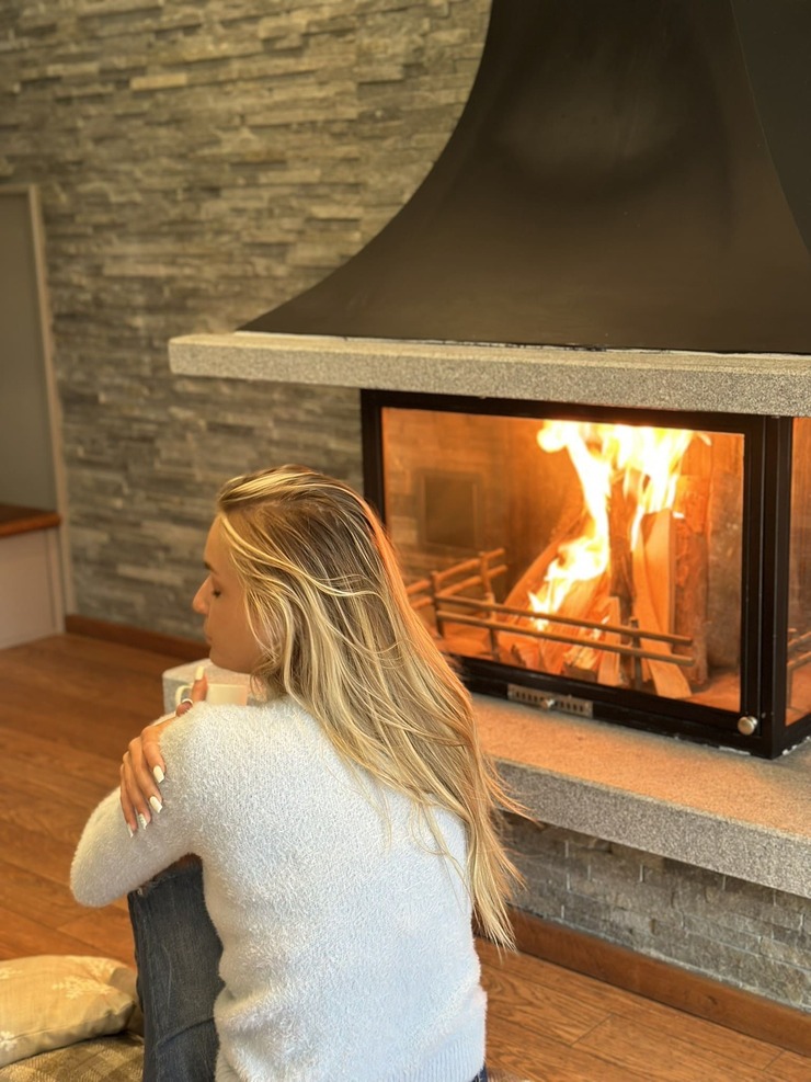An Autumn Family Holiday in the Mountains – Ideas for All Ages - хотел Ruskovets.com Woman holding a cup beside a lit fireplace in a cosy villa at Ruskovets Resort in Dobrinishte
