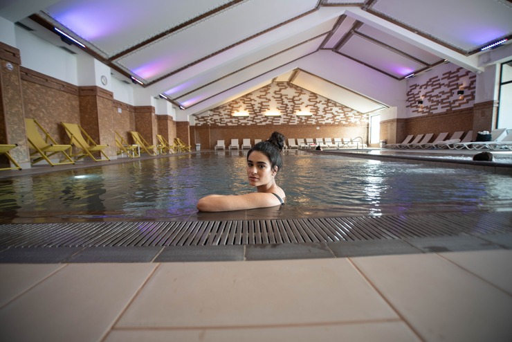 Mineral Water and SPA Breaks in Autumn – Time to Relax and Recharge - хотел Ruskovets.com Woman relaxing at the edge of the indoor mineral pool at Ruskovets Resort in Dobrinishte