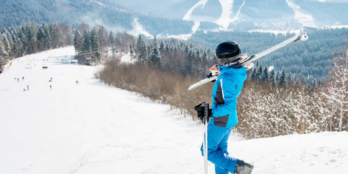 female-skier-walking-down-slope-with-her-skis-shoulder