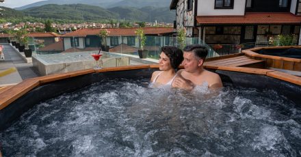 Двама гости се наслаждават на минерална вода в открита дървена вана в Ruskovets Thermal SPA & Ski Resort